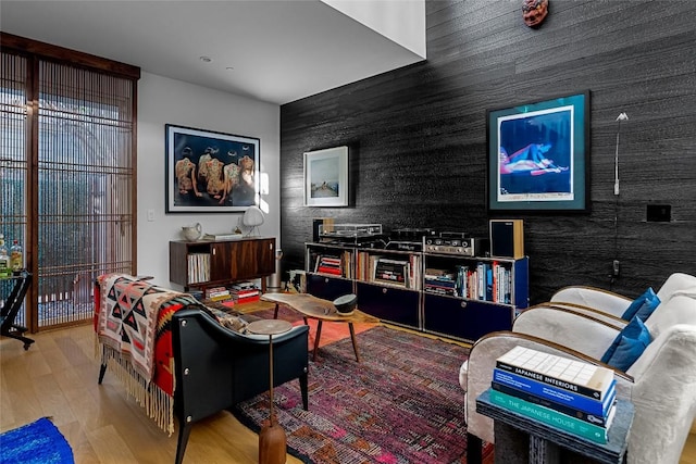 living room with an accent wall and wood finished floors