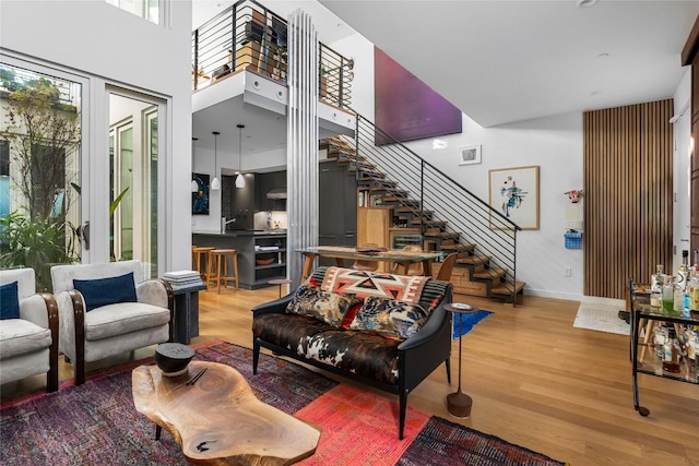 living area with stairway, baseboards, a towering ceiling, and wood finished floors