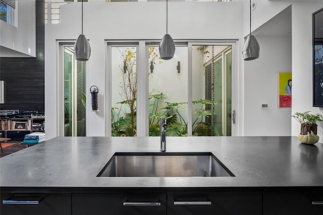 kitchen with decorative light fixtures, dark cabinets, and a sink