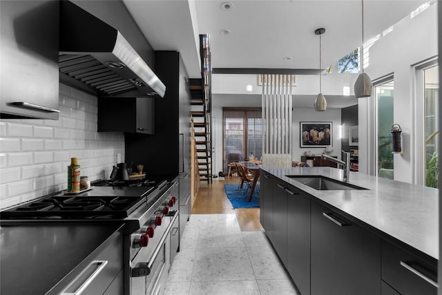 kitchen with modern cabinets, tasteful backsplash, dark cabinetry, wall chimney range hood, and high end range