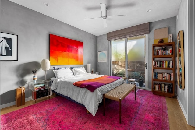 bedroom with baseboards, wood finished floors, a ceiling fan, and access to outside