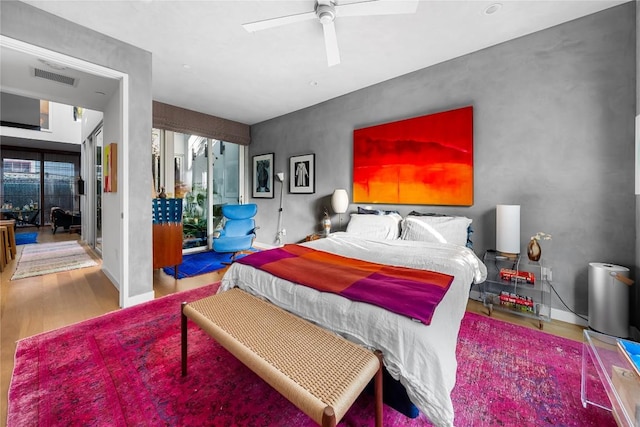 bedroom featuring visible vents, baseboards, ceiling fan, and wood finished floors