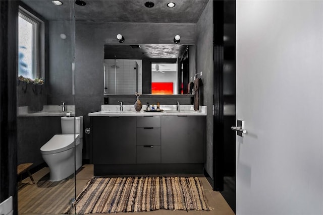 bathroom with a shower with shower door, toilet, and double vanity