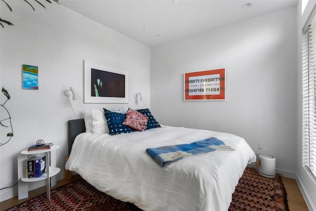 bedroom with baseboards, multiple windows, and wood finished floors