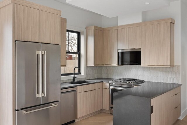 kitchen featuring light brown cabinetry, sink, light hardwood / wood-style flooring, appliances with stainless steel finishes, and backsplash