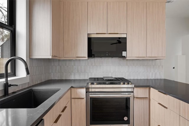 kitchen featuring tasteful backsplash, stainless steel range with gas cooktop, sink, and light brown cabinetry