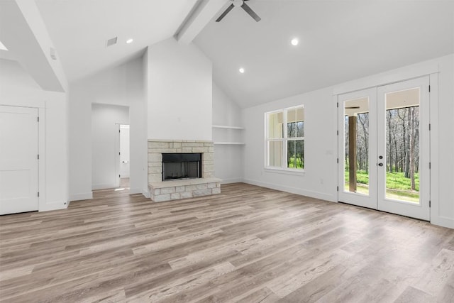 unfurnished living room with a stone fireplace, light hardwood / wood-style floors, french doors, and beamed ceiling