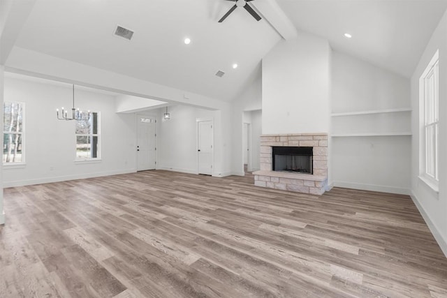 unfurnished living room with ceiling fan with notable chandelier, a fireplace, light hardwood / wood-style floors, and beam ceiling