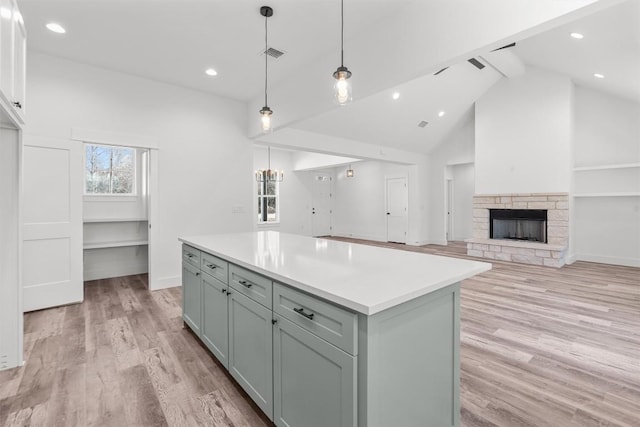 kitchen featuring beam ceiling, a center island, light wood-type flooring, and decorative light fixtures