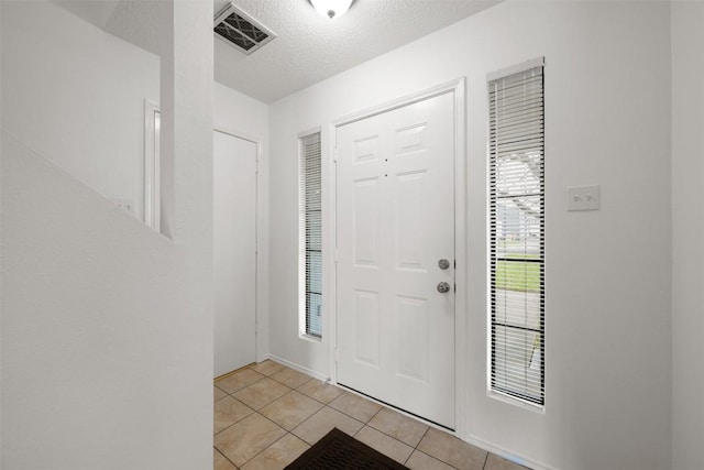 entryway featuring light tile patterned floors and a textured ceiling