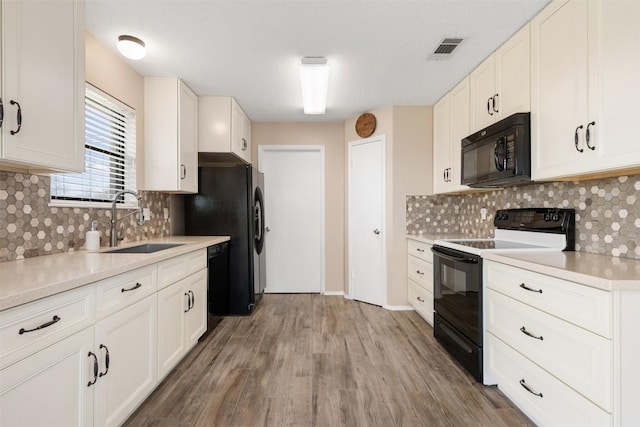 kitchen with sink, black appliances, light hardwood / wood-style flooring, decorative backsplash, and white cabinets