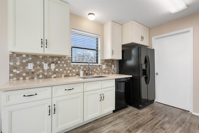 kitchen featuring sink, light hardwood / wood-style flooring, white cabinetry, backsplash, and black appliances