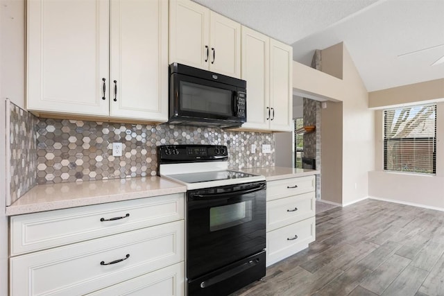 kitchen with wood-type flooring, black appliances, vaulted ceiling, decorative backsplash, and white cabinets