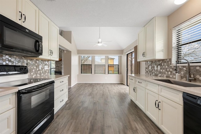 kitchen with lofted ceiling, sink, white cabinetry, dark hardwood / wood-style floors, and black appliances