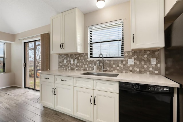 kitchen with black dishwasher, sink, white cabinets, and decorative backsplash