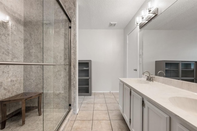 bathroom featuring tile patterned floors, vanity, a shower with door, and a textured ceiling