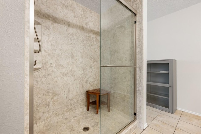 bathroom featuring tile patterned flooring, a textured ceiling, and tiled shower