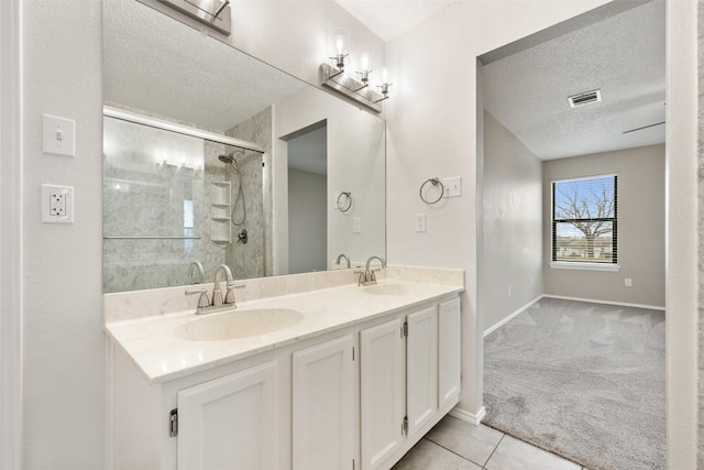 bathroom with tile patterned flooring, vanity, a textured ceiling, and a shower with shower door