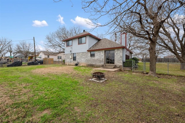 rear view of house featuring a lawn and an outdoor fire pit