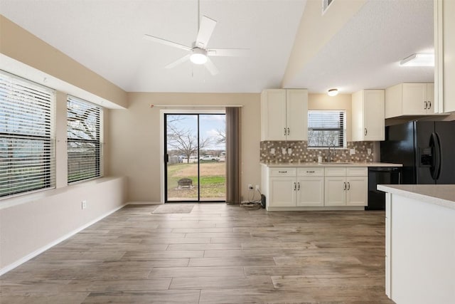 kitchen with white cabinetry, sink, backsplash, light hardwood / wood-style floors, and black appliances