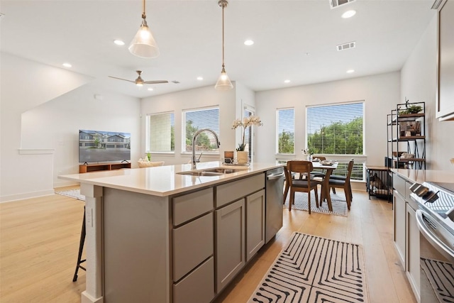 kitchen featuring recessed lighting, a sink, appliances with stainless steel finishes, gray cabinets, and light wood finished floors