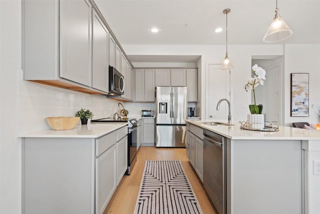 kitchen featuring stainless steel appliances, a sink, and gray cabinetry