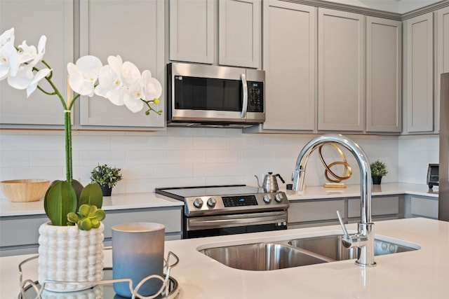 kitchen featuring tasteful backsplash, appliances with stainless steel finishes, sink, and gray cabinetry