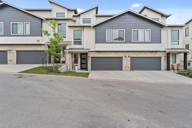 townhome / multi-family property featuring a garage, stone siding, concrete driveway, and stucco siding