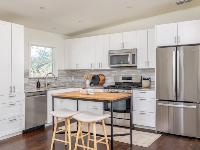 kitchen featuring lofted ceiling, butcher block counters, sink, white cabinetry, and stainless steel appliances