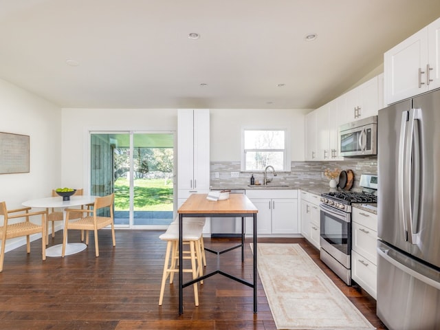 kitchen featuring sink, white cabinets, dark hardwood / wood-style flooring, decorative backsplash, and stainless steel appliances