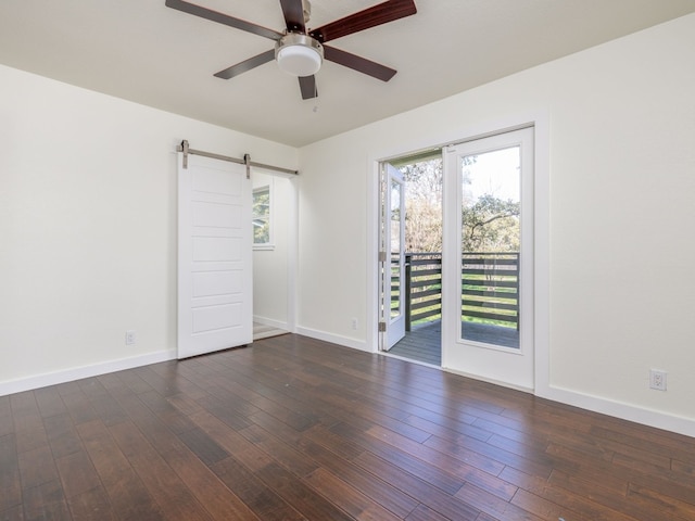 spare room with ceiling fan, a barn door, and dark hardwood / wood-style flooring