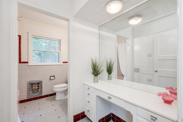 bathroom with tile patterned floors, toilet, heating unit, tile walls, and vanity