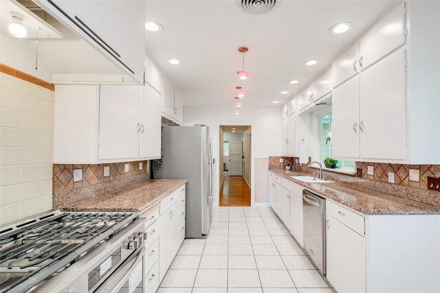 kitchen featuring sink, light tile patterned floors, stainless steel appliances, light stone countertops, and white cabinets