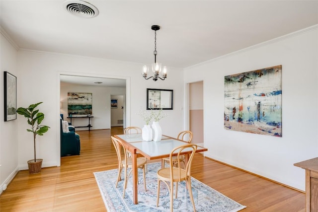 dining space featuring crown molding, wood-type flooring, and a chandelier