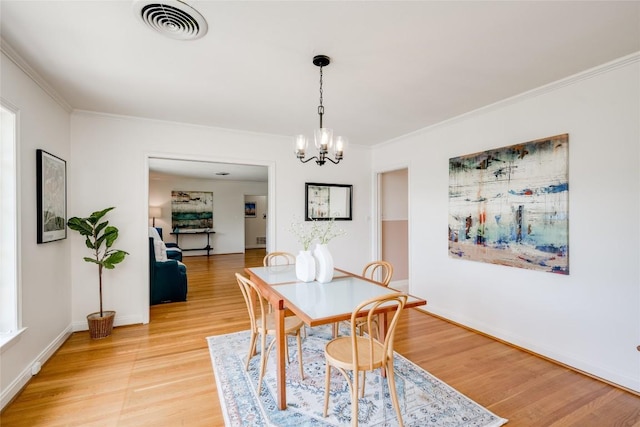 dining area with crown molding, a chandelier, and light wood-type flooring