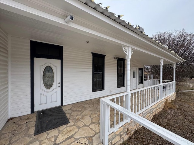 view of exterior entry featuring covered porch