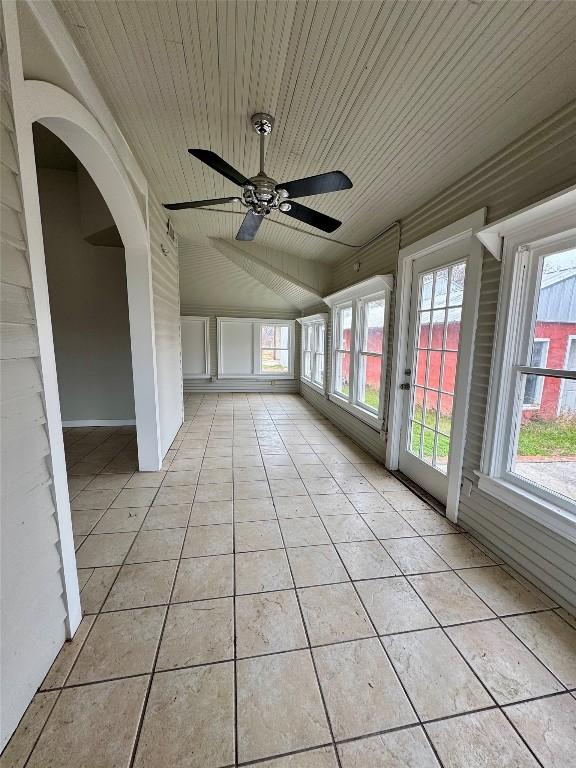 unfurnished sunroom with wood ceiling, vaulted ceiling, and ceiling fan