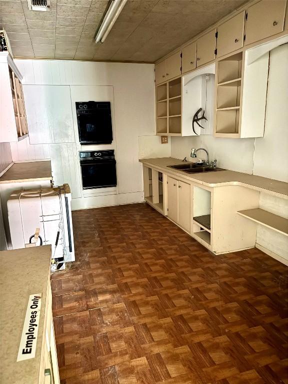 kitchen with sink, black oven, and dark parquet floors