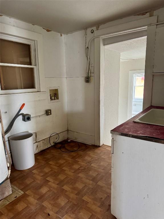 clothes washing area with sink, hookup for a washing machine, and dark parquet flooring