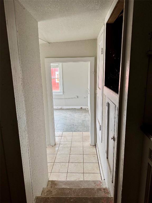 corridor featuring light tile patterned floors and a textured ceiling