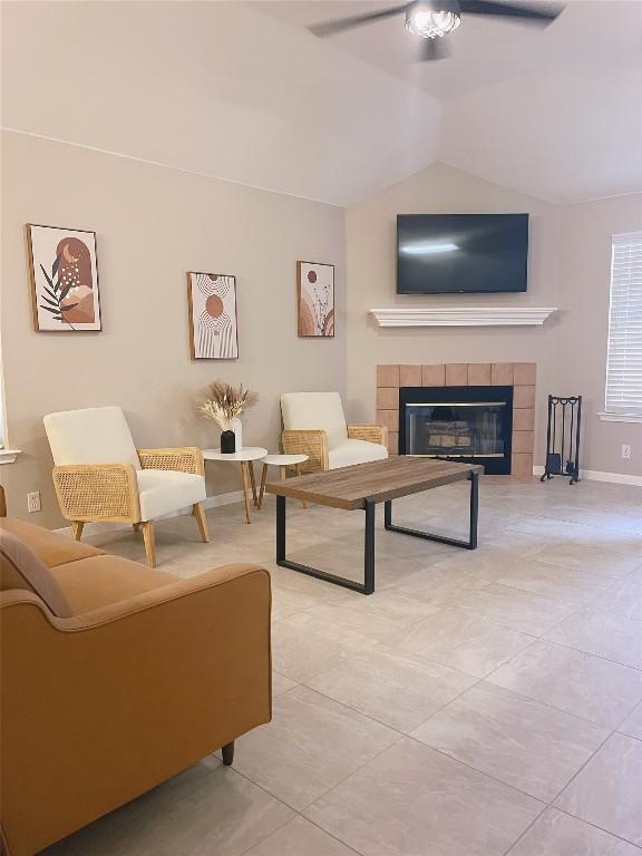 tiled living room featuring ceiling fan, lofted ceiling, and a fireplace