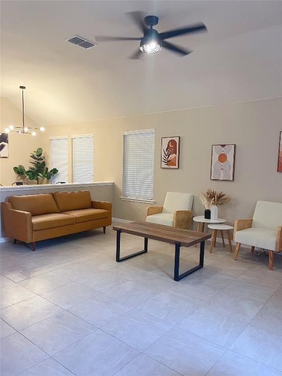 living room featuring lofted ceiling and ceiling fan with notable chandelier