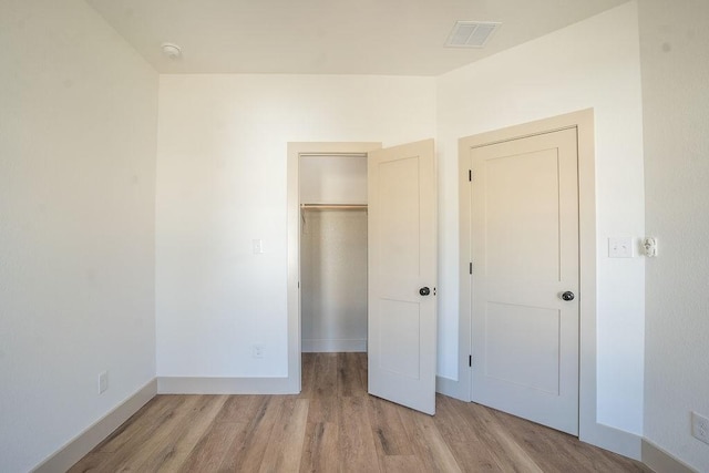 unfurnished bedroom featuring a closet, a spacious closet, and light hardwood / wood-style flooring