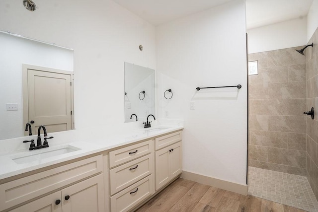 bathroom featuring hardwood / wood-style flooring, vanity, and a tile shower