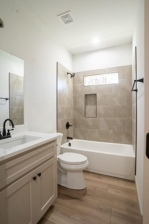 full bathroom with vanity, hardwood / wood-style flooring, toilet, and tiled shower / bath