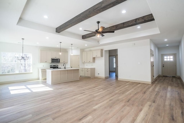 kitchen with hanging light fixtures, stainless steel appliances, an island with sink, and light wood-type flooring