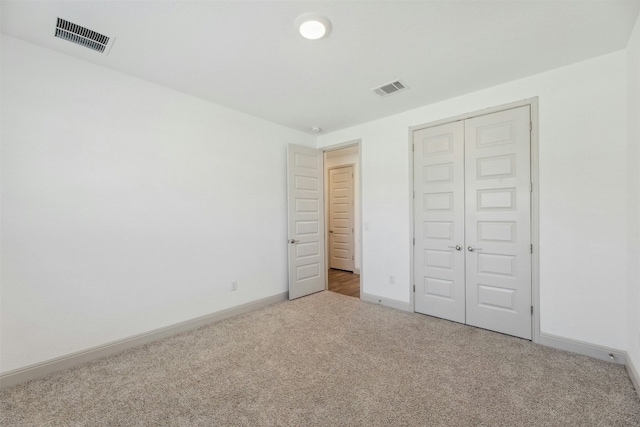 unfurnished bedroom with light colored carpet and a closet