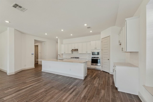 kitchen with sink, white cabinetry, a center island with sink, appliances with stainless steel finishes, and dark hardwood / wood-style flooring