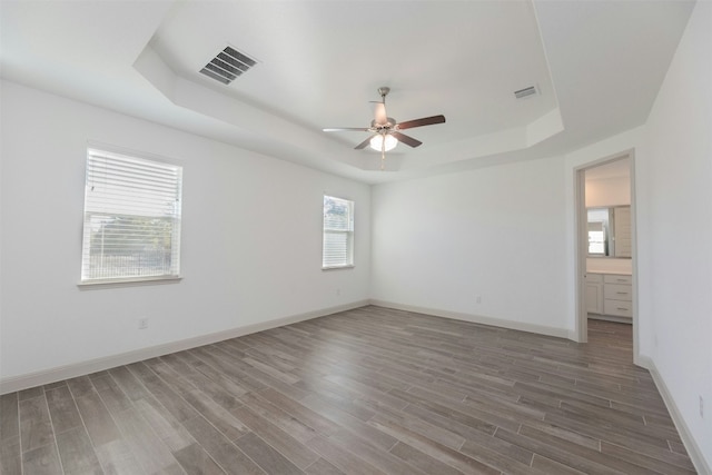 unfurnished room with ceiling fan, dark hardwood / wood-style flooring, and a raised ceiling