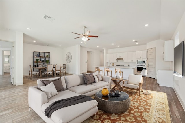 living room with ceiling fan and light wood-type flooring